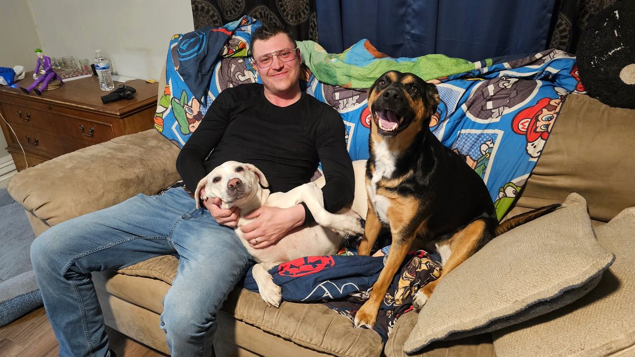 Man sitting on couch with two happy dogs.