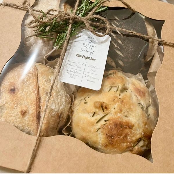 Mini flight box with artisan breads tied with rosemary sprigs in a rustic box.