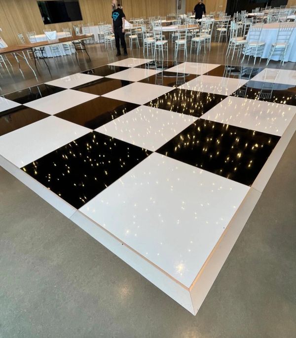 Shiny black and white checkered floor reflecting lights.