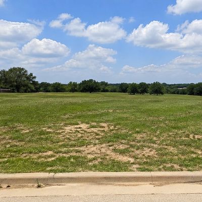 Wide open grassy field under a partly cloudy sky.