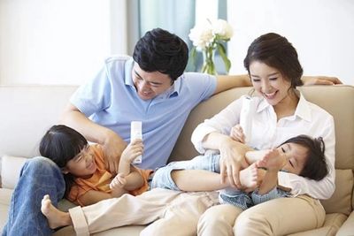 Happy family playing and laughing together on a couch.