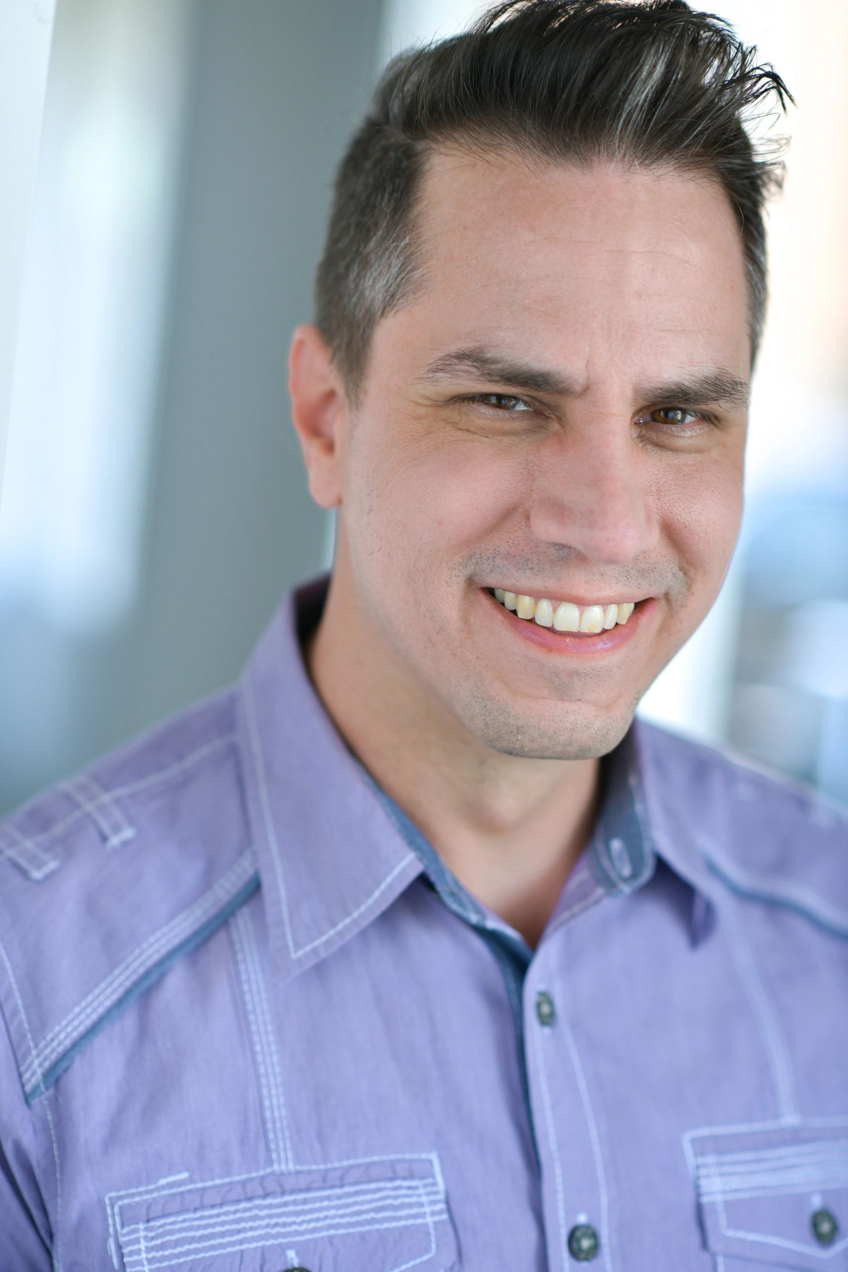 Smiling man wearing a purple shirt.