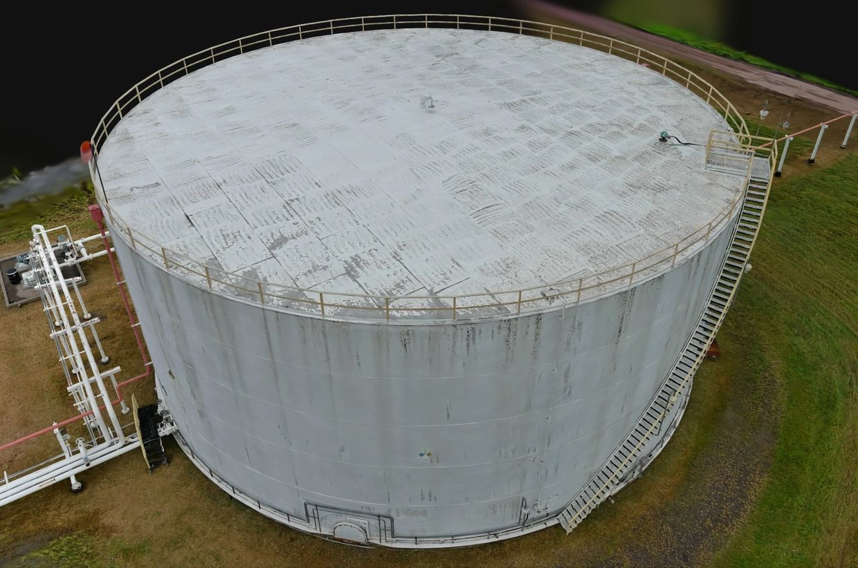 Large industrial storage tank with surrounding pipes and staircase.