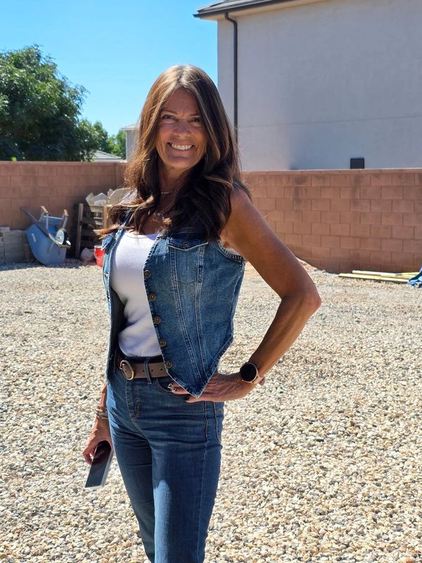 Woman posing outdoors in denim outfit with a smile.