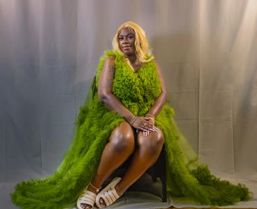 A person in a vibrant green ruffled dress poses against a neutral backdrop.