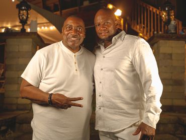 Two men in white shirts posing together warmly at night.