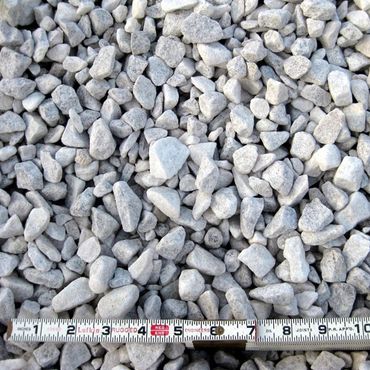 Close-up of light gray gravel stones with a measuring tape for scale.