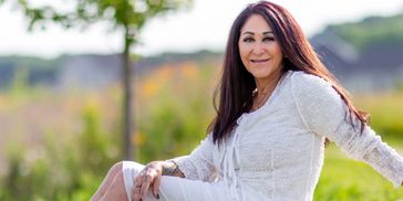 Traycee in a white dress sitting on a rock