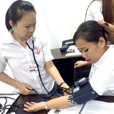 Healthcare worker checking blood pressure of a patient.