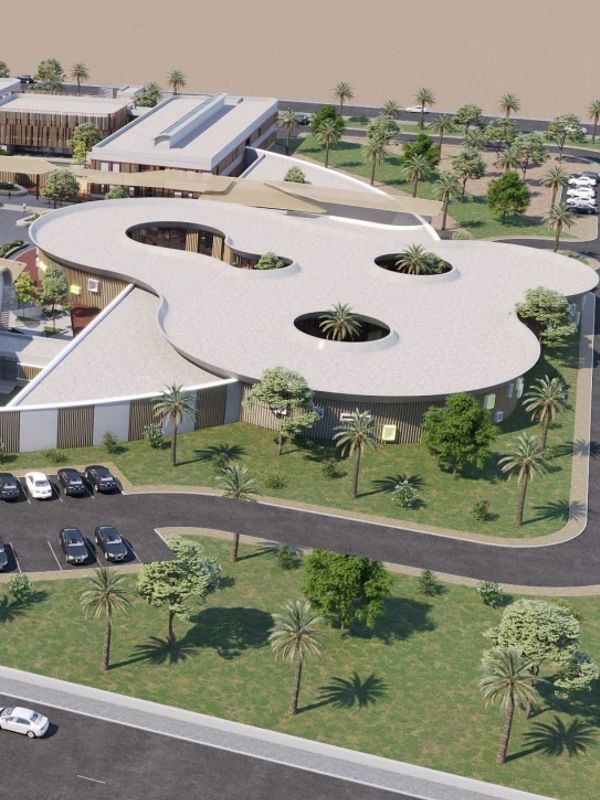 Aerial view of a modern building with a unique design and surrounding greenery.