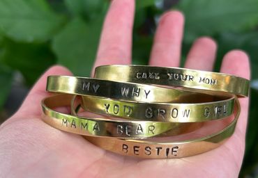 Hand stamped cuffs that say bestie, mama bear, you grow girl, my why, and call your mom.