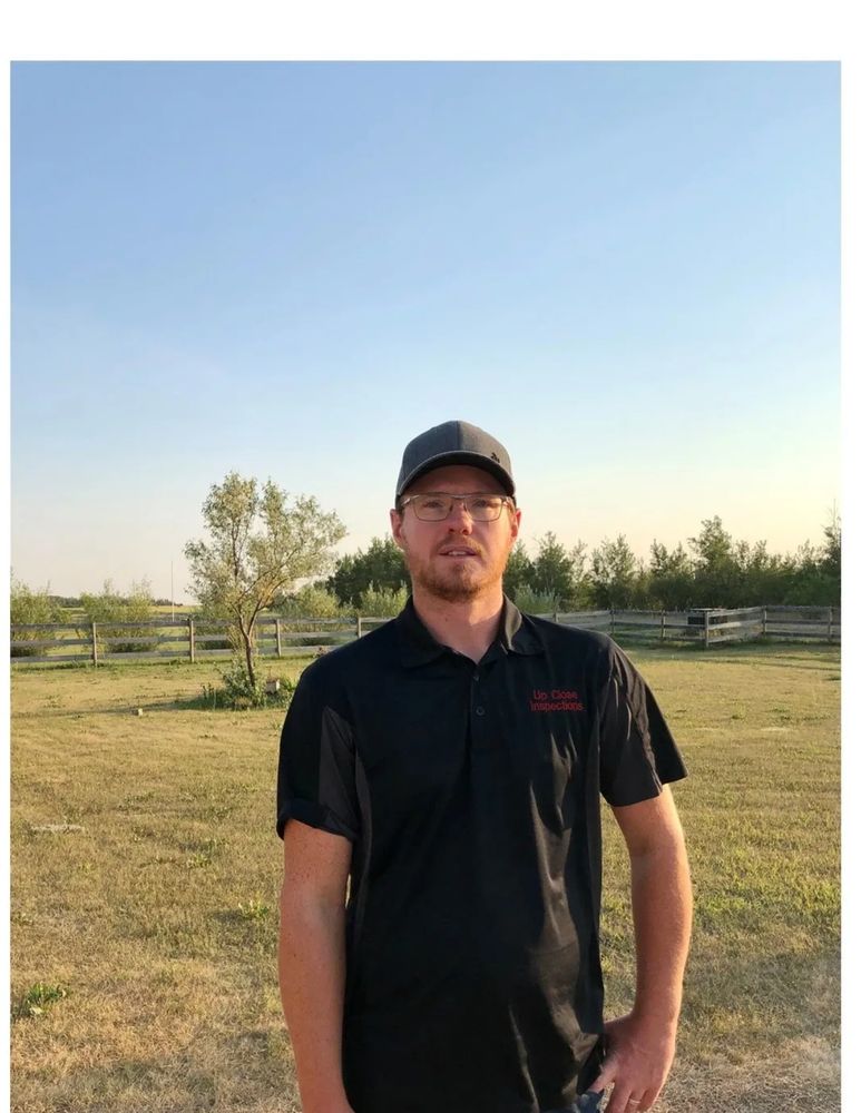 Man in black polo and cap standing outdoors.