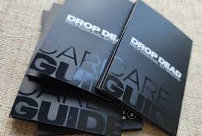 Black card guides titled 'DROP DEAD' stacked on a surface.
