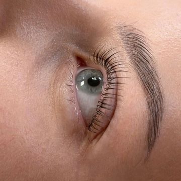 Close-up of a human eye with long eyelashes and defined eyebrow.