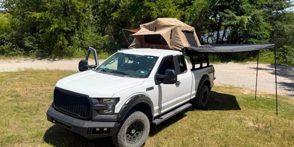 White pickup truck with roof tent and side awning set up.