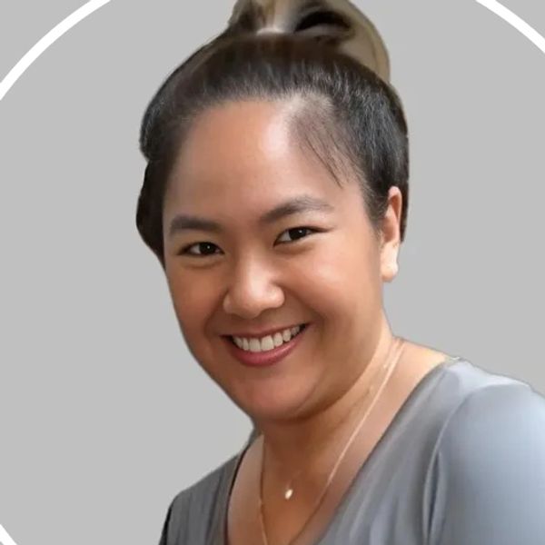 Smiling woman with hair tied back, wearing a gray top.