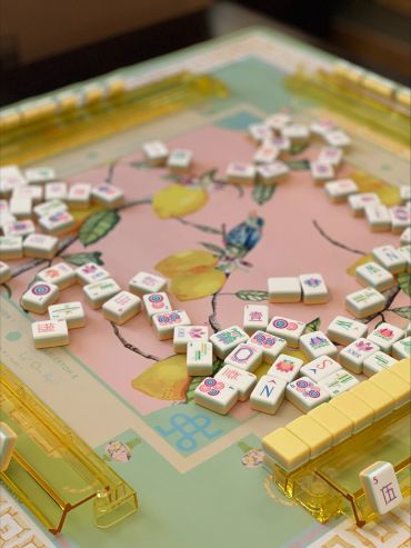 Colorful Mahjong tiles scattered on a floral game board with yellow tile racks.