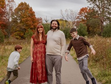 A family of four enjoying a walk on a fall day outdoors.