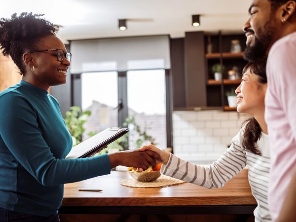 Two women shaking hands in a friendly meeting at a kitchen table.