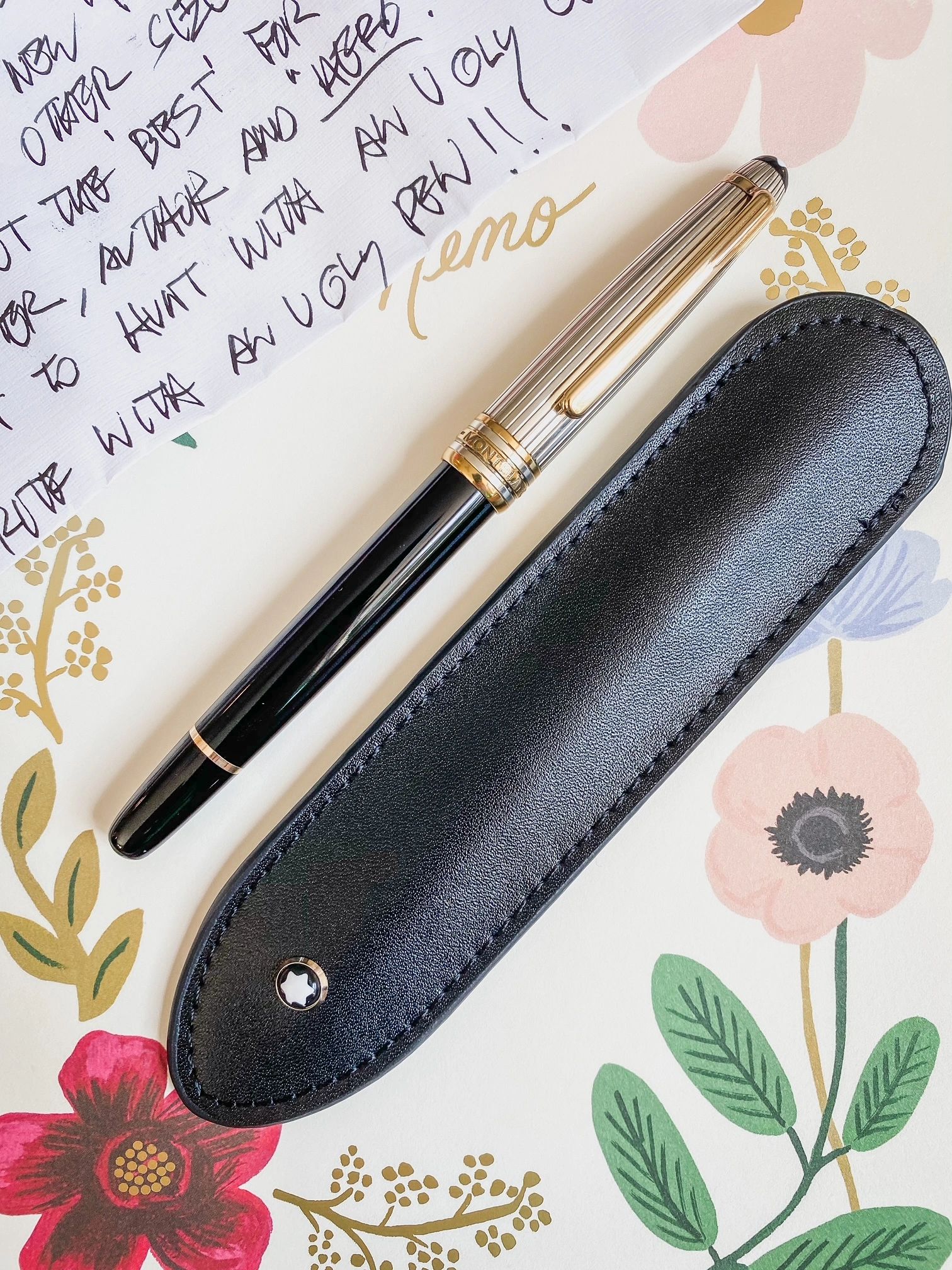 Writing pen with case on top of notepad with handwritten nte.