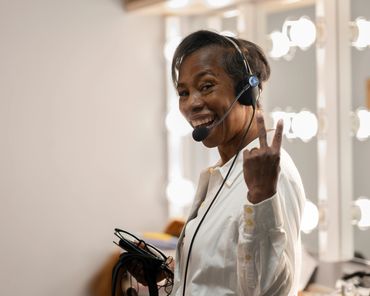 Smiling woman wearing a headset showing a peace sign.