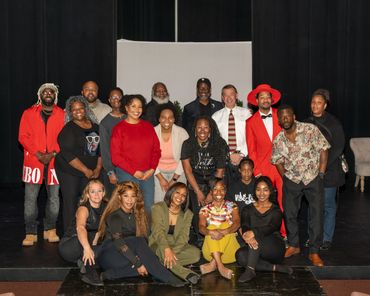 A diverse group of people posing together on a stage, smiling.