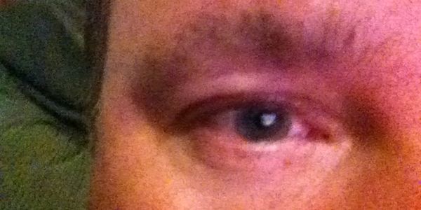 Close-up of a human eye with visible skin texture and eyebrow.