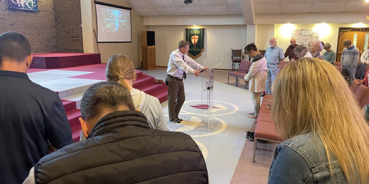 People praying in a church service with a speaker at the podium.