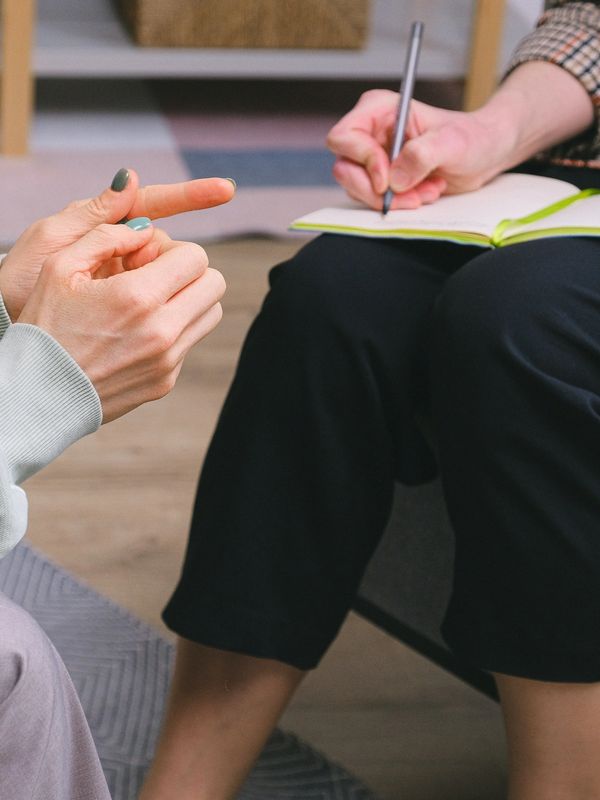 A counsellor taking notes while speaking with a client