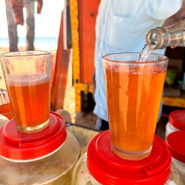 Refreshing orange drink being poured into a glass at a street stall.