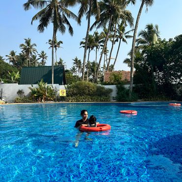 A woman and child in a pool with palm trees in the background.
