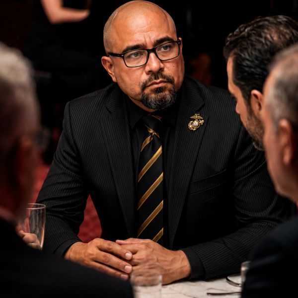 Man in suit and striped tie in a serious discussion at a table.