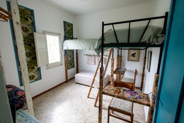 Bright room with a loft bed and wooden study desks underneath.