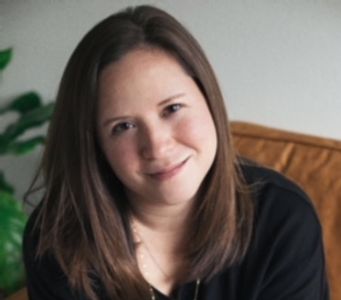 Smiling woman with brown hair sitting indoors.