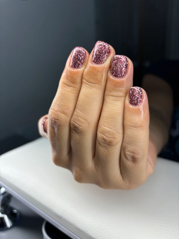 A glittery pink gel nail manicure
