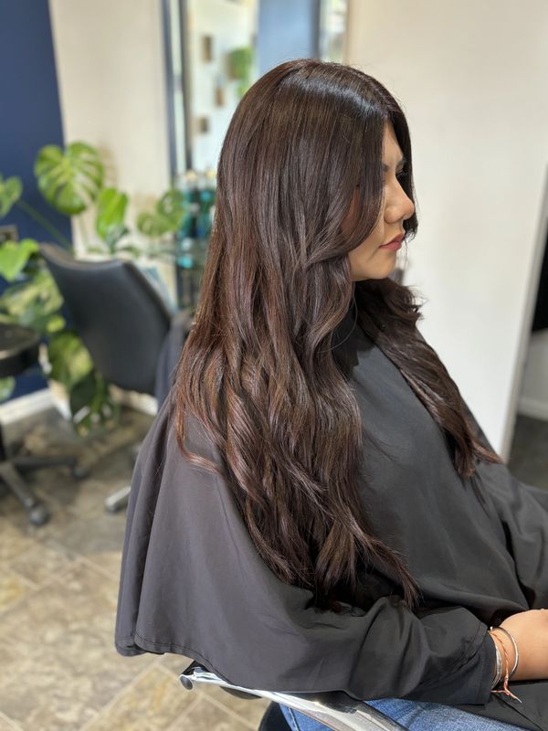 Women with long dark brown shiny curled hair.