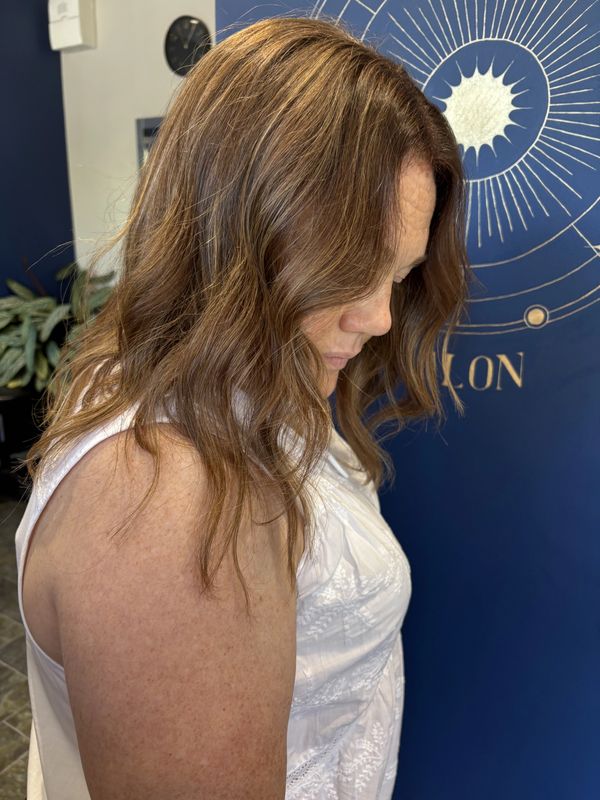 Women's hair showing brown colouring with fine highlights and a soft wave curl.