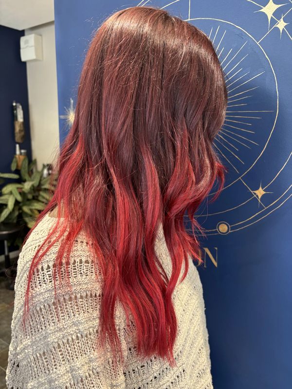 Women with long curled hair with an ombre purple to red colouring.