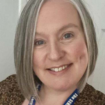 Smiling woman with gray hair and blue lanyard.