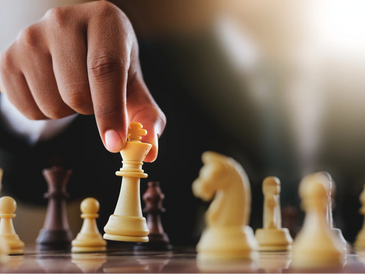 Hand moving a white king chess piece on a chessboard.