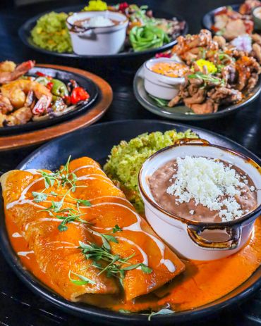 Shrimp enchiladas smothered in a rich bell pepper, seafood crema sauce