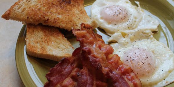 A breakfast plate with bacon, eggs, and toasted bread.