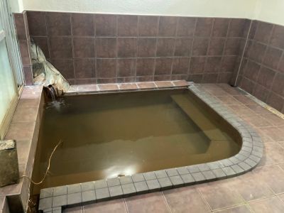 Indoor small pool with brownish water and tiled surroundings.