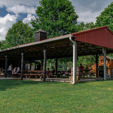 Outdoor picnic shelter with people and playground.