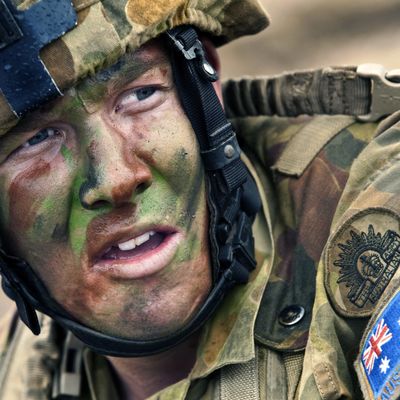 An Australian soldier in uniform. His face is covered in camouflage paint.