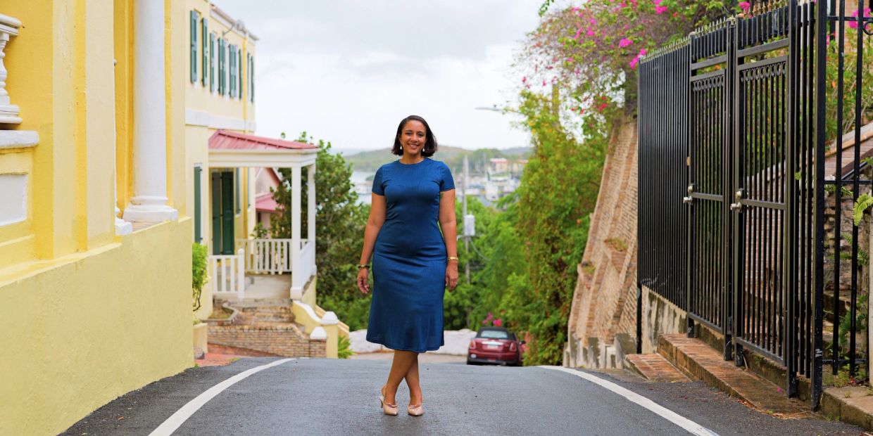 Woman in a blue dress standing on a street.