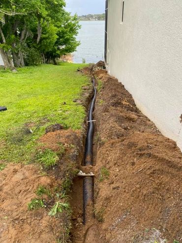French drain installation beside a home to improve yard drainage.