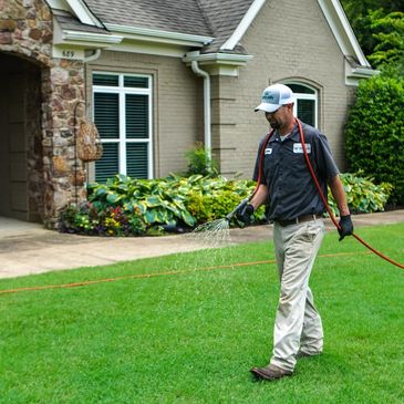 Evergreen Turf Care technician applying a lawn treatment to a residential lawn.