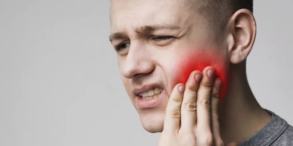 Man holding his cheek in pain, indicating a toothache.
