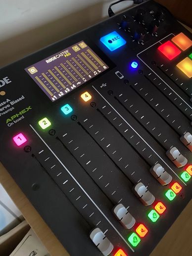 Close-up of a RODECaster Pro audio mixing console with colorful illuminated buttons and sliders.